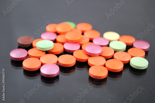 Bright multicolored tablets closeup on black background