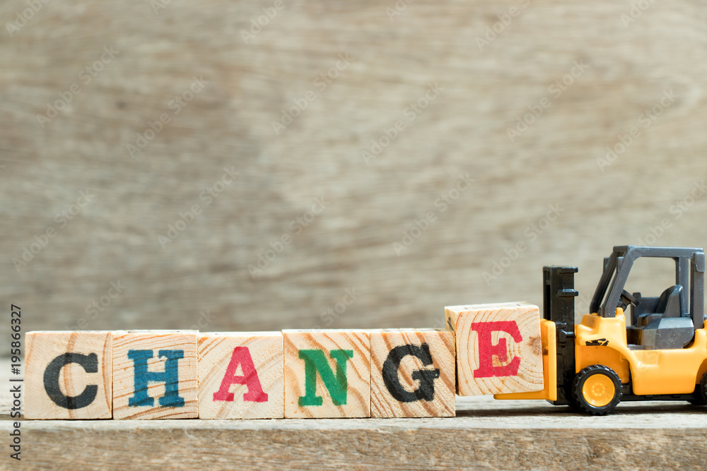 Fototapeta premium Toy yellow forklift hold block letter e to complete word change on wood background