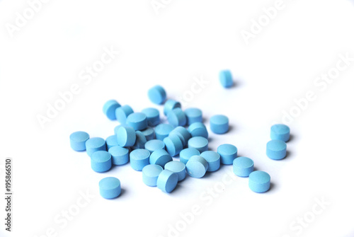 Small bright blue tablets closeup on white background
