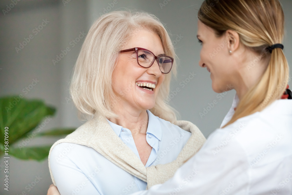 Beautiful aged woman in glasses embracing young adult lady and laughing, smiling attractive senior older mother happy to hug grown-up daughter, warm sincere family bonding having fun together Beautiful aged woman in glasses embracing young adult lady and laughing, smiling attractive senior older mother happy to hug grown-up daughter, warm sincere family bonding having fun together