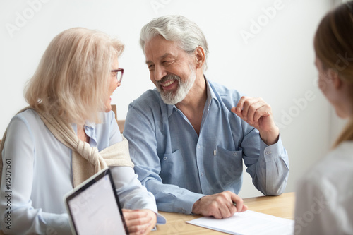 Happy senior family talking smiling at meeting with financial advisor, older clients ready to buy medical health life insurance consulting broker, aged retired couple making real estate deal about to