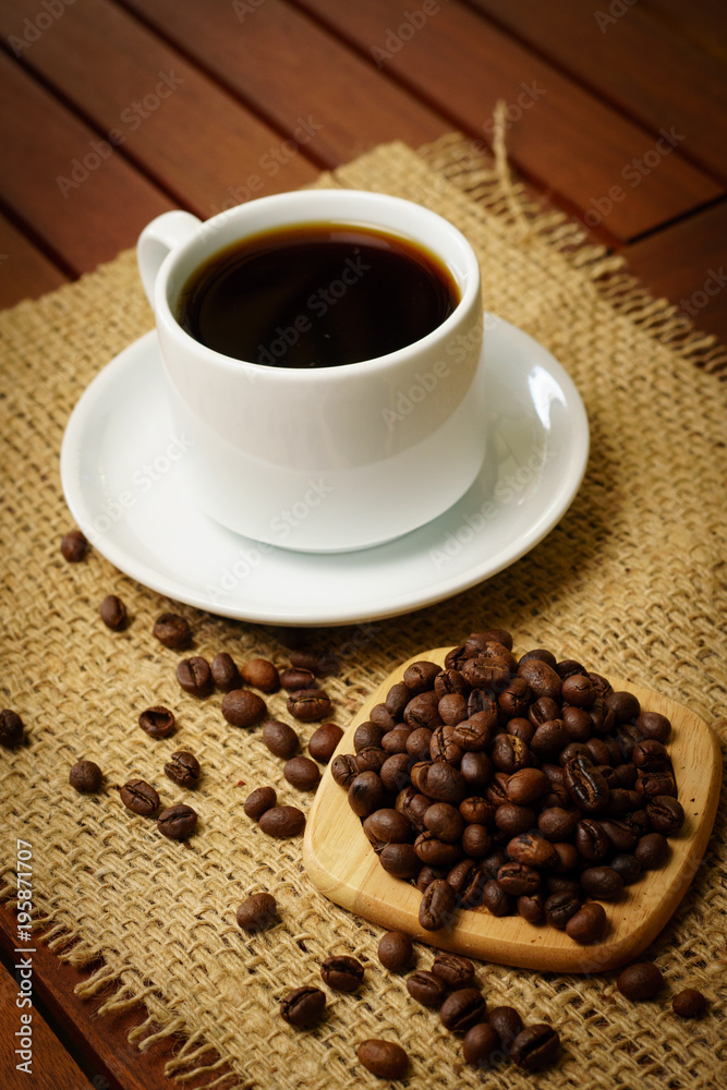 Cup of black coffee and coffee beans on burlap