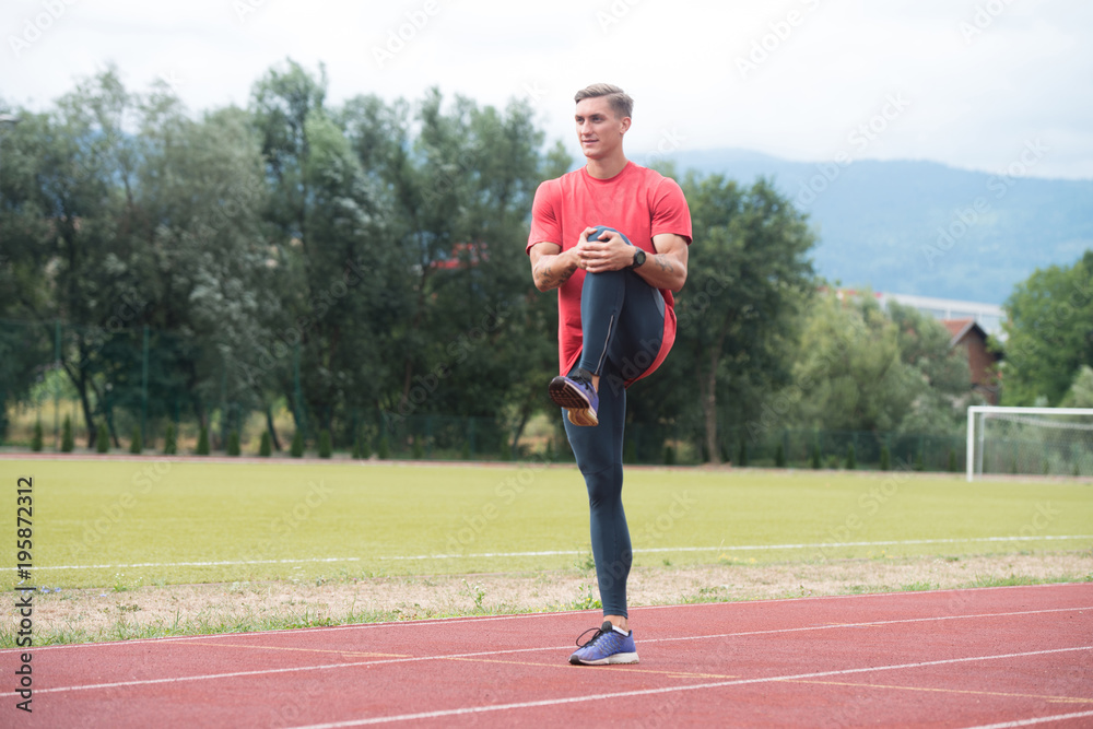 Young Male Runner Warming Up Before Running