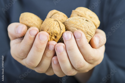 Manos de un niño ofreciendo un puñado de nueces photo