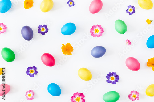 Easter eggs and primrose flowers on white background. Easter concept. Flat lay, top view