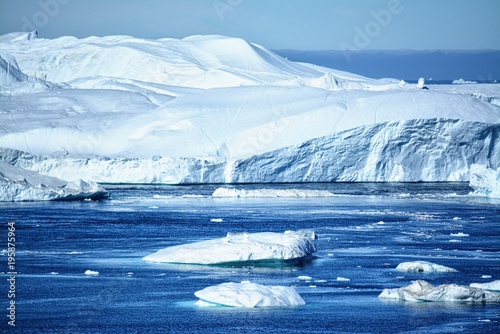 Ilulissat Greenland - massive icebergs in the Disko Bay / Baffin Bay on a sunny day blue sky, ice sea photo