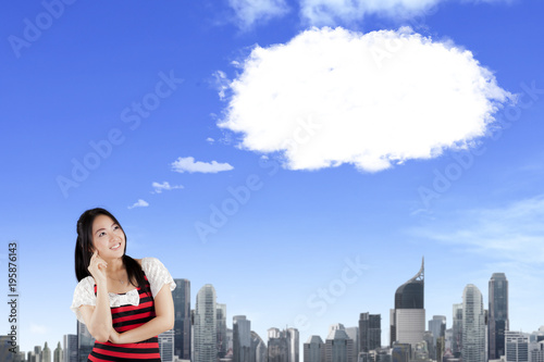 Smiling oriental woman thinking and looking up with blank bubble speech