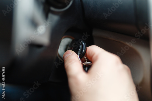 The driver of the man gets a car with a key. The hand inserts the key into the ignition and starts the car. Hand put the car key to the keyhole starting the car.