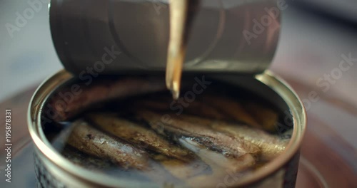 Using fork takes a smoked sardines from a tin can