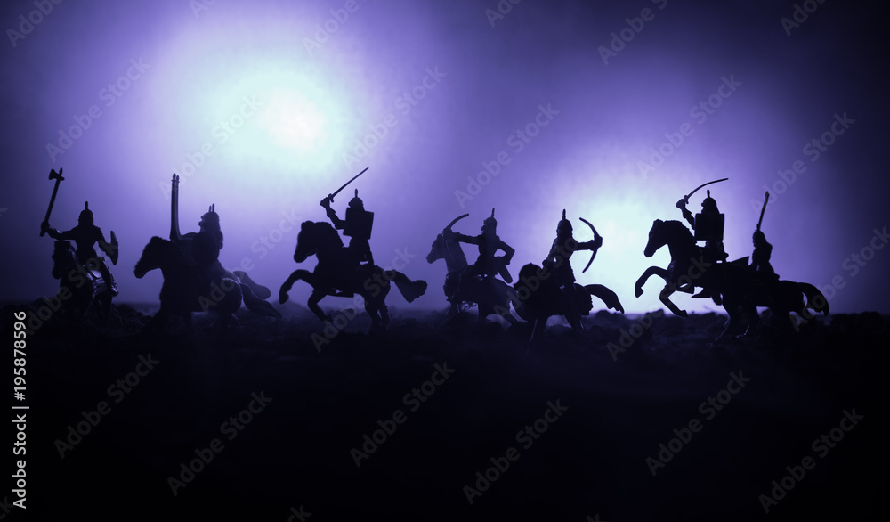 Fototapeta premium Medieval battle scene with cavalry and infantry. Silhouettes of figures as separate objects, fight between warriors on dark toned foggy background. Night scene.