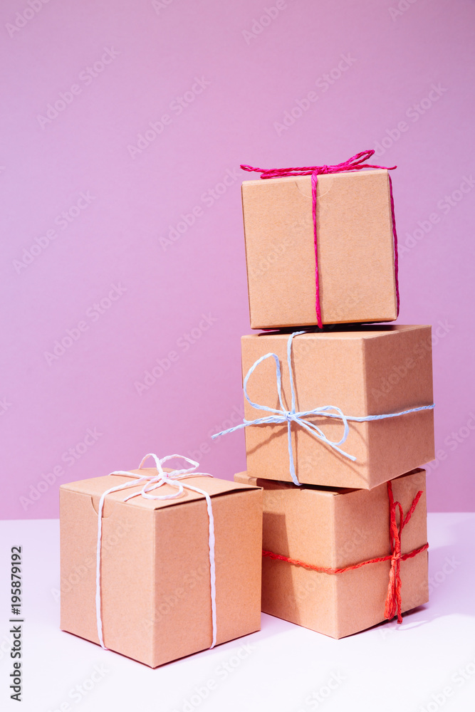 Craft cardboard gift boxes on the solid pink background. Holiday and gift concept