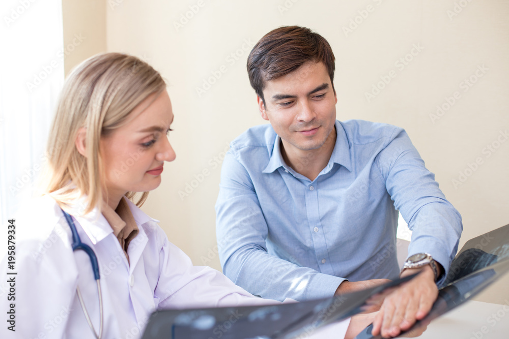 Attractive female doctor showing x-ray films to patient at clinic. Medical and Health care concept. Attractive female doctor showing x-ray films to patient at clinic. Medical and Health care concept.