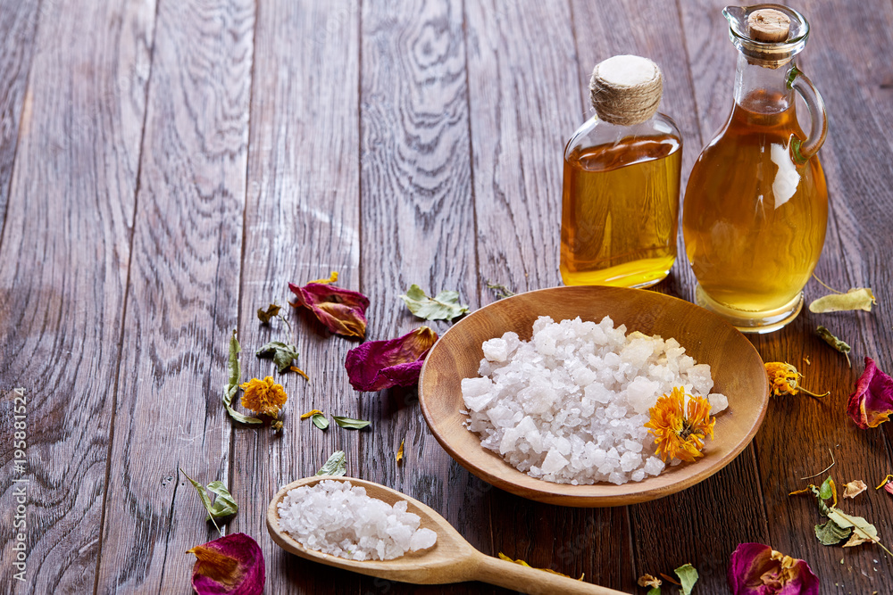 SPA concept: composition of spa treatment with natural sea salt, aromatic oil and flowers on wooden background SPA concept: composition of spa treatment with natural sea salt, aromatic oil and flowers on wooden background
