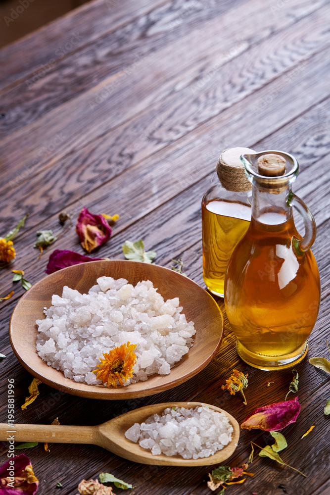 SPA concept: composition of spa treatment with natural sea salt, aromatic oil and flowers on wooden background SPA concept: composition of spa treatment with natural sea salt, aromatic oil and flowers on wooden background