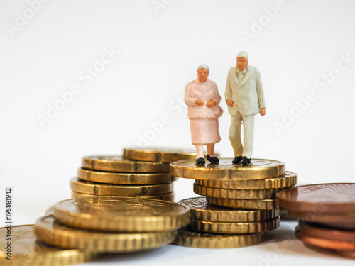 Miniature senior couple stand on pile of Euro coins. Retirement planning concept.
