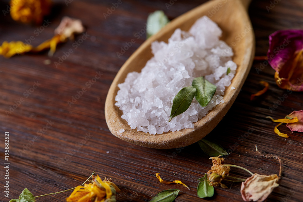 SPA concept: composition of spa treatment with natural sea salt, aromatic oil and flowers on wooden background SPA concept: composition of spa treatment with natural sea salt, aromatic oil and flowers on wooden background