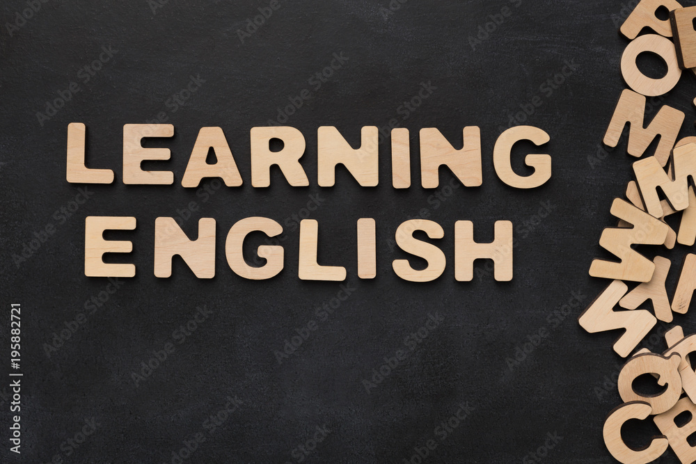 Fototapeta premium Learning English spelled with wooden letters on black background