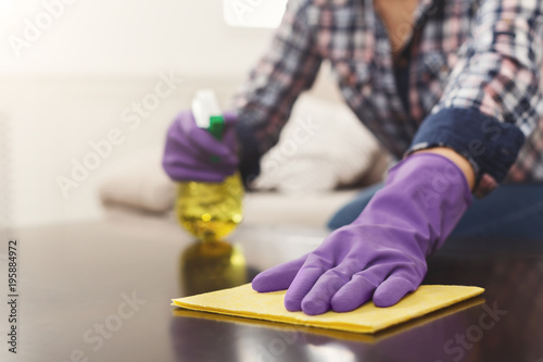 Woman using spray cleaner on wooden surface