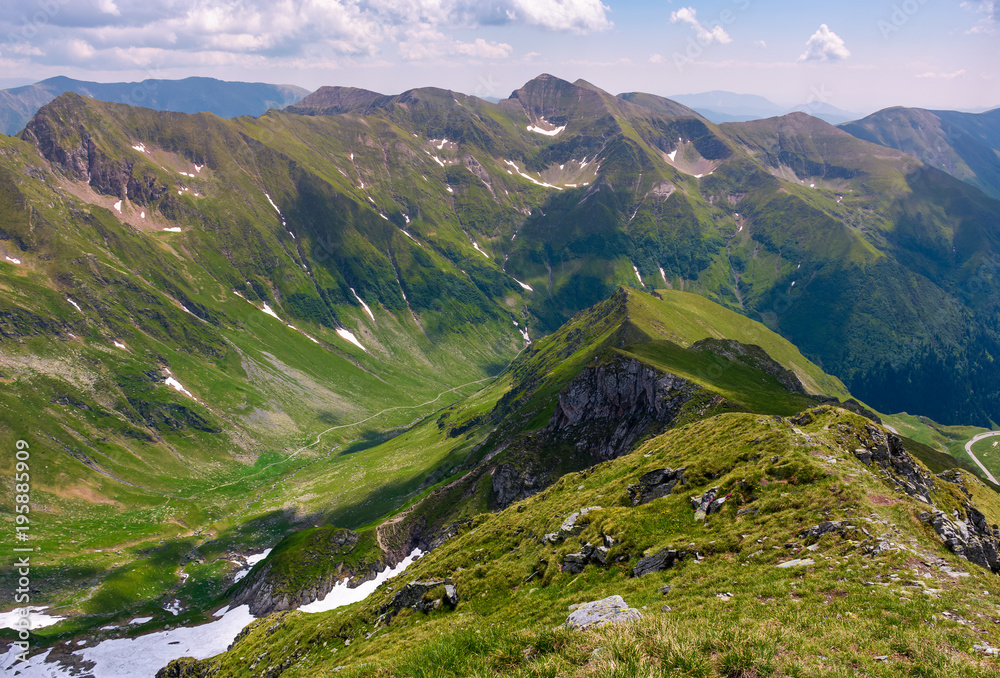 Naklejka premium ridge with grassy slopes and cliffs. Southern Carpathian mountains in a far distance. beautiful summer scenery of Romania