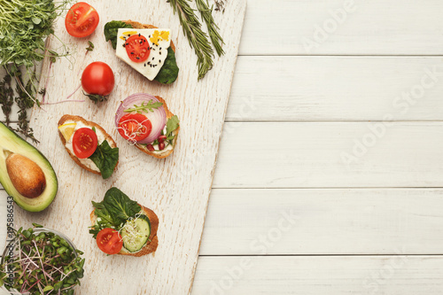 Variety of healthy vegetarian sandwiches on white wood, top view
