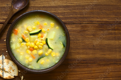 Vegetarian corn and courgette chowder served in rustic bowl, photographed overhead with natural light (Selective Focus, Focus on the top of the soup)