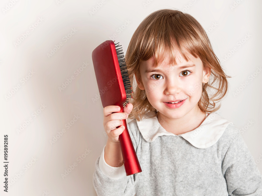 Little baby girl holds comb and combing her hair on light background. Stock  Photo | Adobe Stock