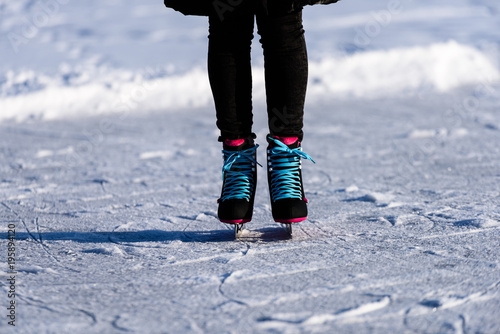 young woman in black coat skating on the frozen lake in snow