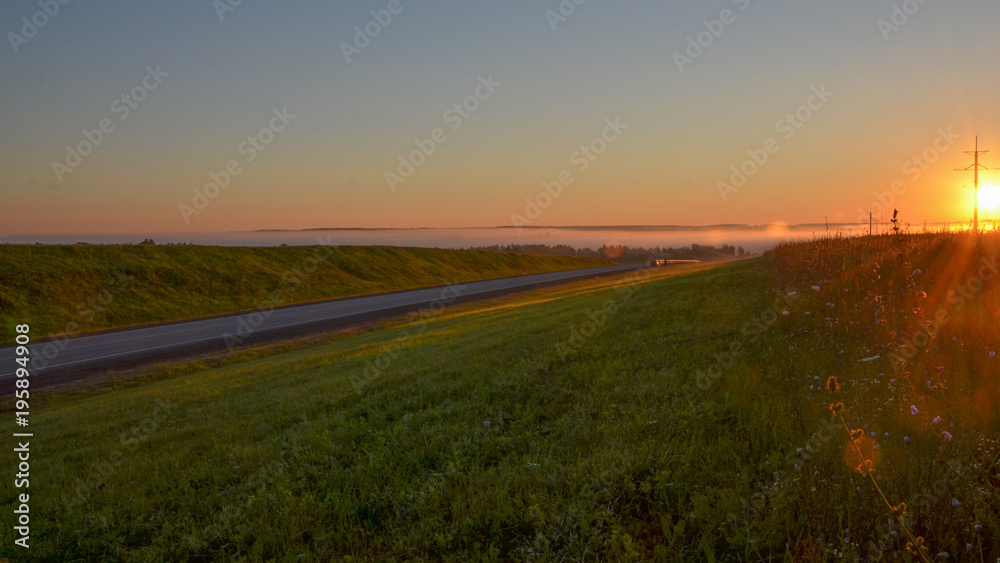 highway passing grasslands and hills at sunrise with heavy fog covering river valley Kaluga region, Russia