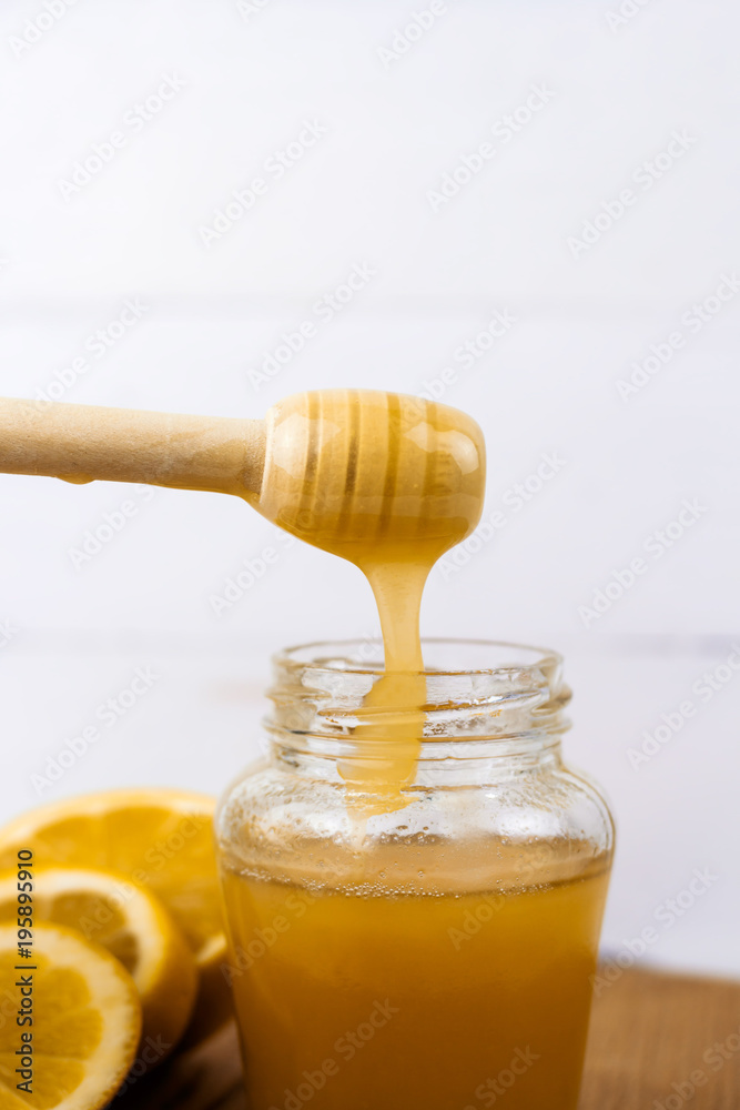 jar of honey and lemon slices on a wooden board light background jar of honey and lemon slices on a wooden board light background