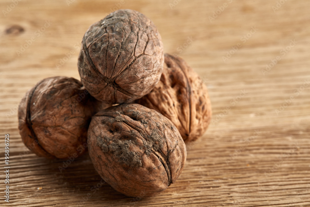 A stack of hard shells of walnuts piled together on light grey fabric cotton tablecloth, selective focus A stack of hard shells of walnuts piled together on light grey fabric cotton tablecloth, selective focus