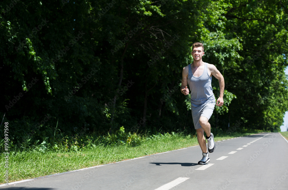 Young man jogging on treadmill in park, copy space