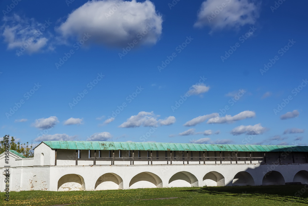 White wall of the monastery against the background of excellent blue sky with clouds