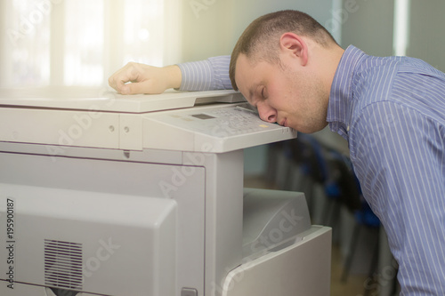 exhausted businessman or office manager sleeping on a multifunction printer or copier