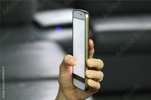 Holding smart phone in hand with blank white screen photo