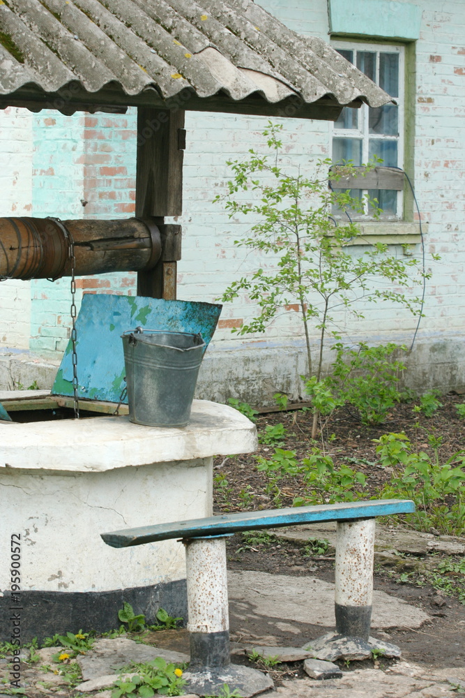 Obraz premium pit (well) near the old house in garden