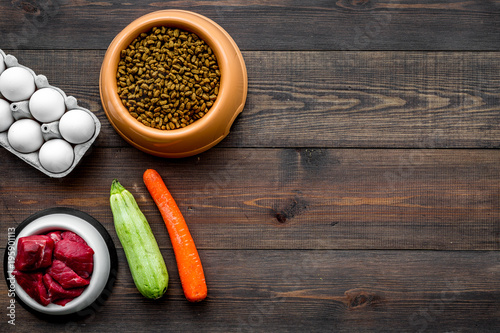 Dry food for dogs and cats based on raw meat and vegetables on dark wooden backgroud top view copy space