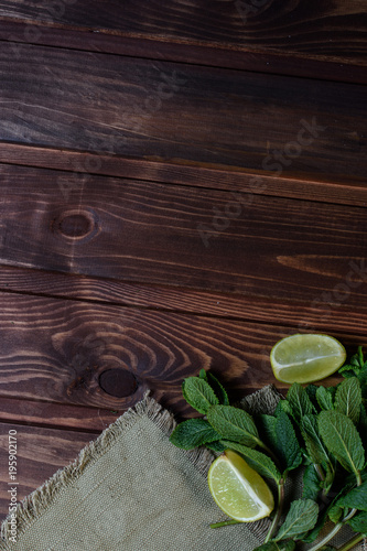 Bundle of fresh mint and lime slice on a napkin on an old wooden background.