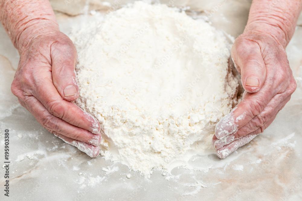 Old hands make a hill of flour, close-up Old hands make a hill of flour, close-up