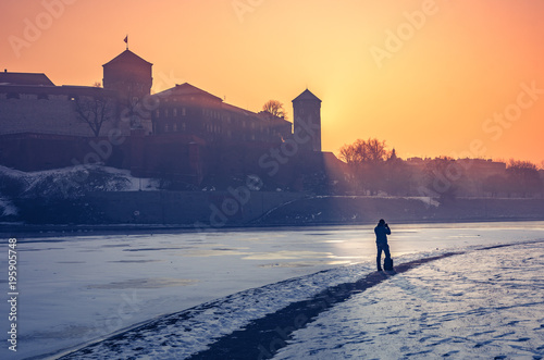 Krakow, Poland, photographer looking at Wawel Castle in the winter over frozen Vistula river, sunrise photo