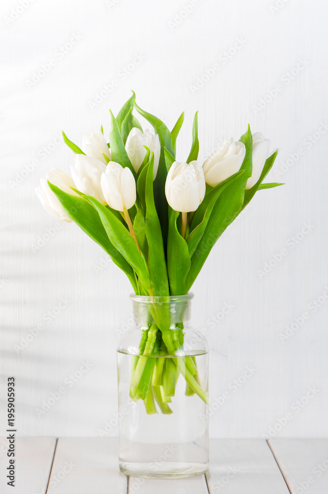 Bouquet of white tulips in glass vase on the white wooden table Bouquet of white tulips in glass vase on the white wooden table