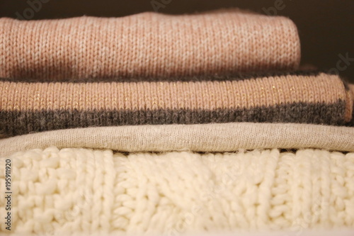 textures wool and cotton clothes of the white light pink and gray colors on the shelves