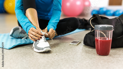 Woman tying shoelace before training in gym