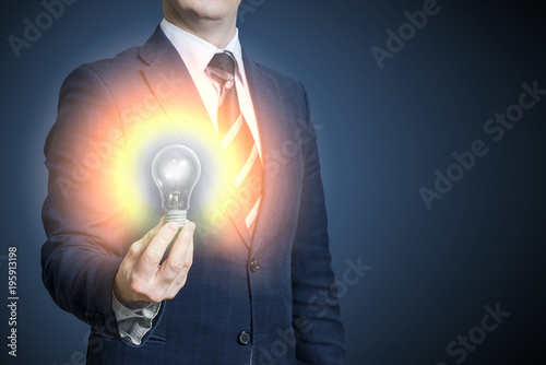 Hand of businessman holding illuminated light bulb, idea, innovation and inspiration concept. Bright idea in hand businessman