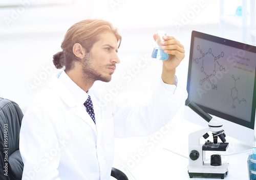 scientist in the chemical lab examines a flask with a substance