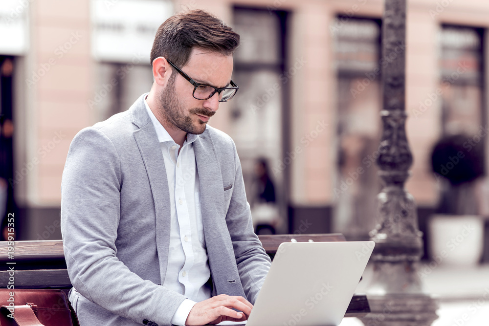 Businessman with laptop sitting on a bench