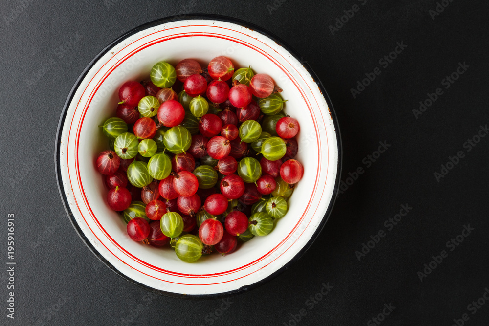 Fresh gooseberries in an enamel bowl on dark background Fresh gooseberries in an enamel bowl on dark background