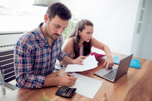 Young couple looking at family finance papers. © ivanko80