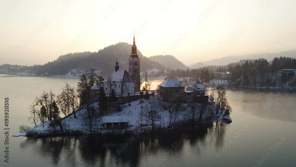 Flying around beautiful Bled lake landmark with church on the island at sunrise Flying around beautiful Bled lake landmark with church on the island at sunrise