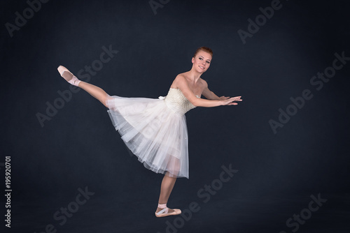 the ballerina in pointes and a white dress dances on a dark background