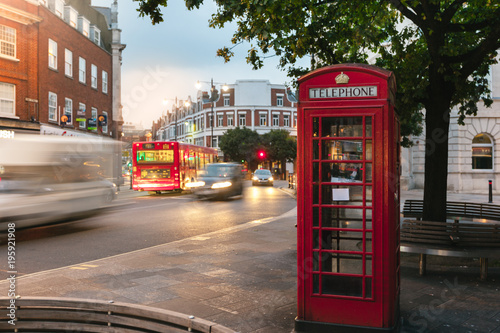 a view of the iconic red telephone box in London with moving cars in the background